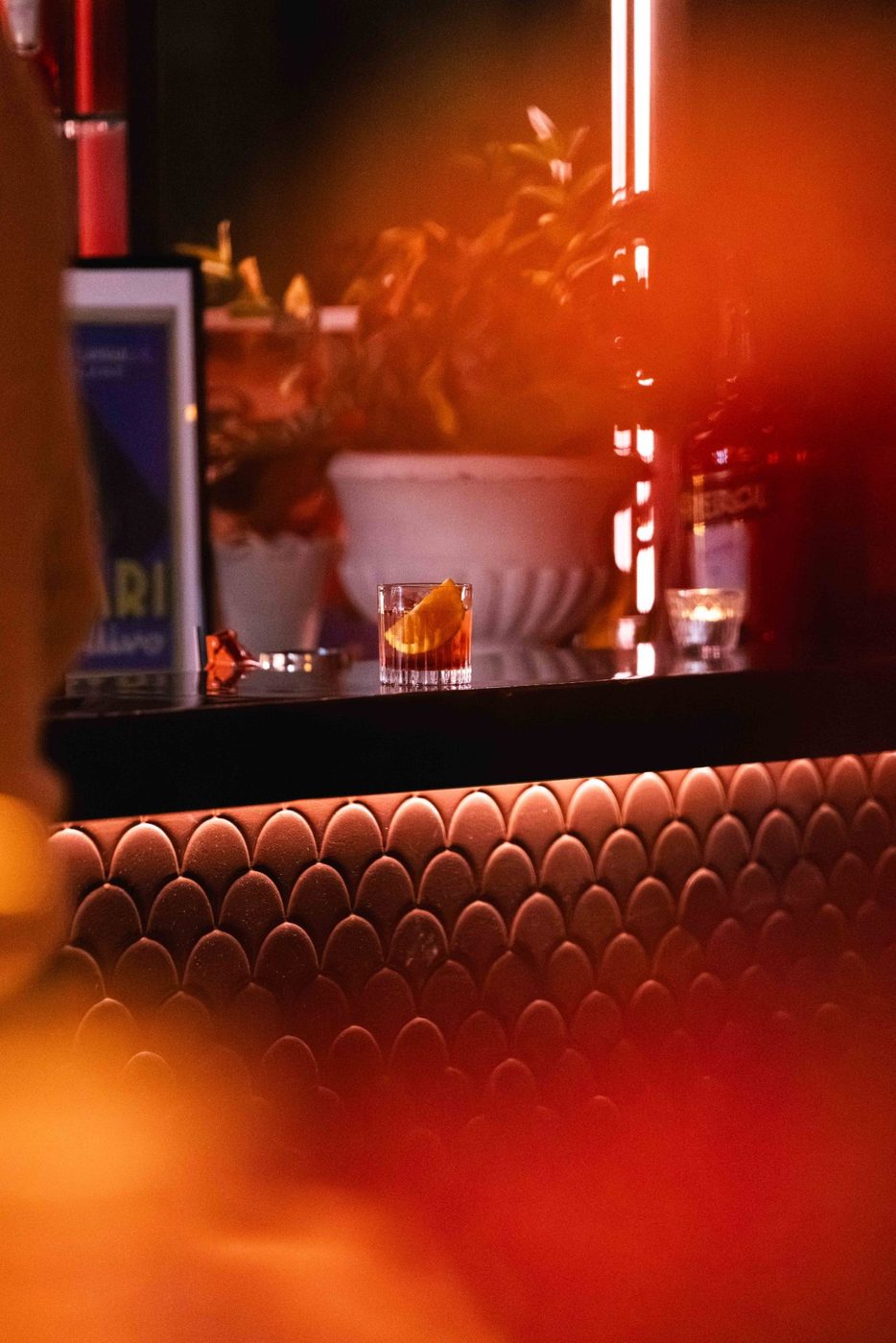 The Negroni bar on Level 1, glowing red over the scalloped bar front