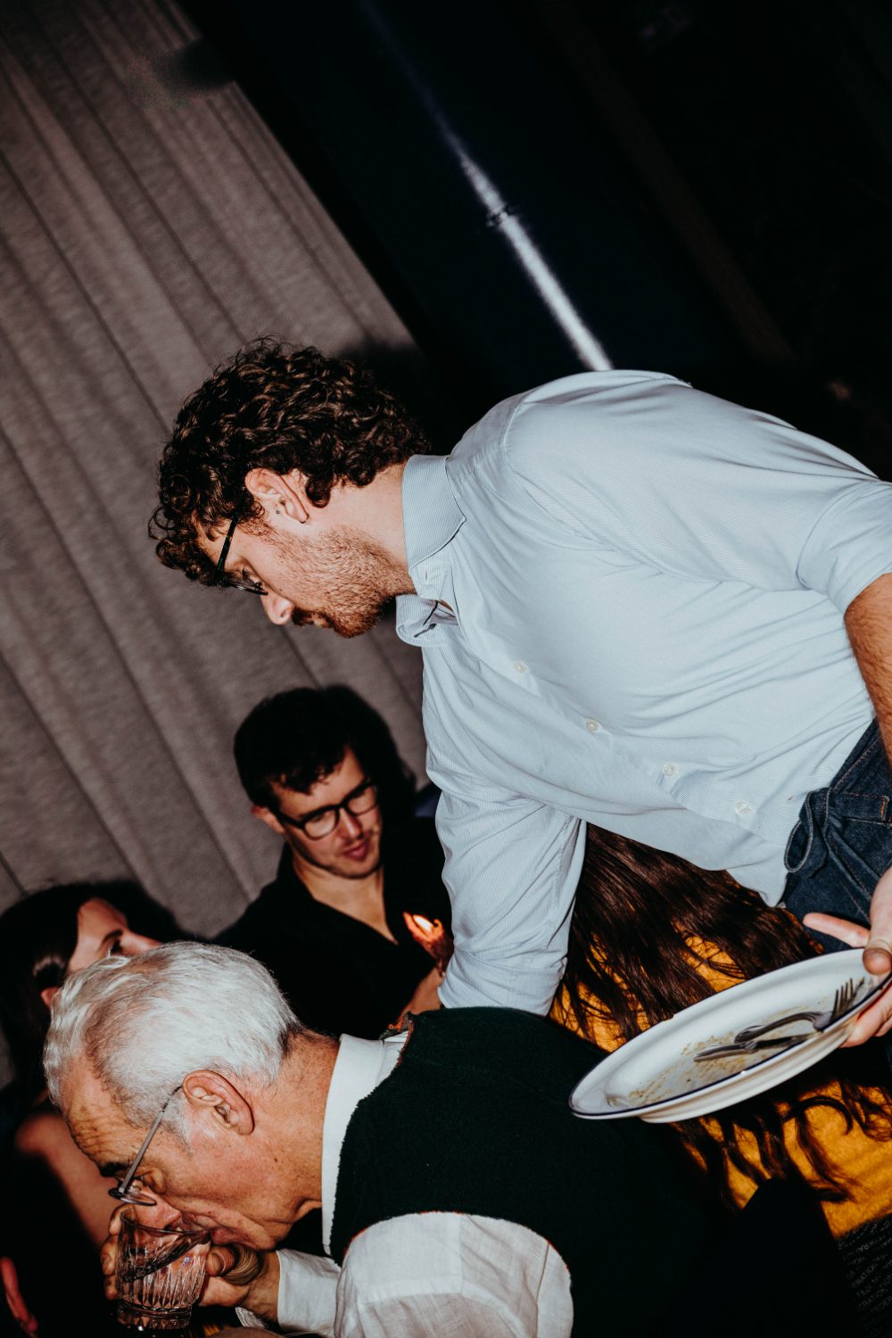 A waiter clearing plates at a busy private dinner