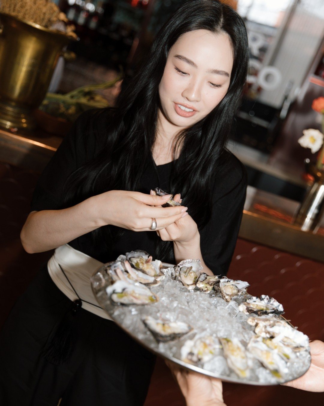 A guest at the bar choosing an oyster from a tray on ice