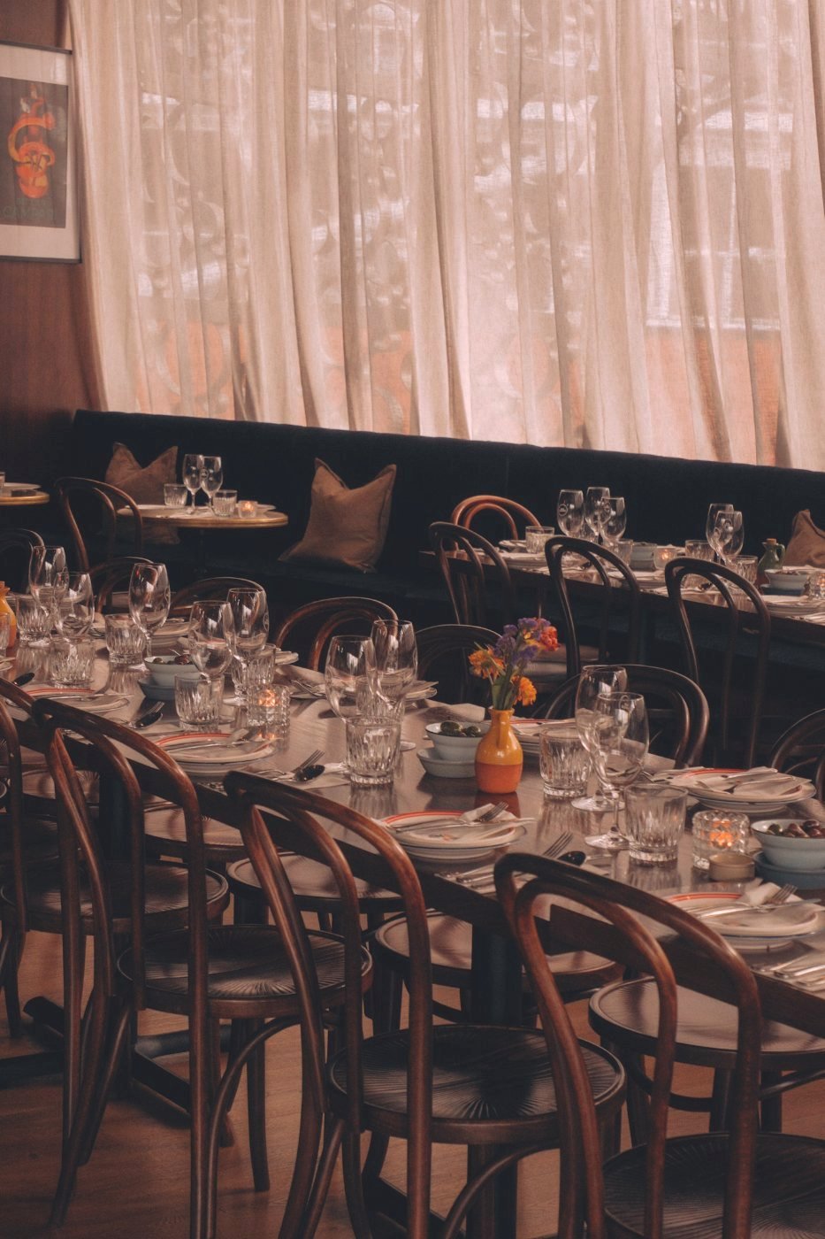 The restaurant dining room at Bar Franco — velvet banquette, bentwood chairs and set tables