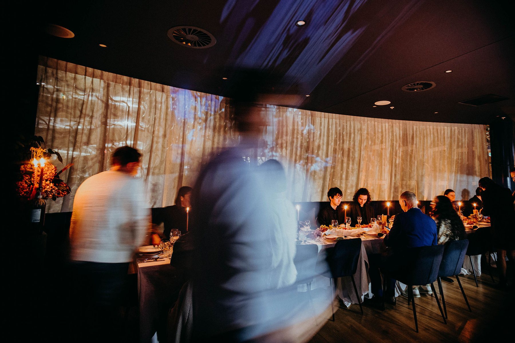 A seated dinner upstairs with film projected across the curtains