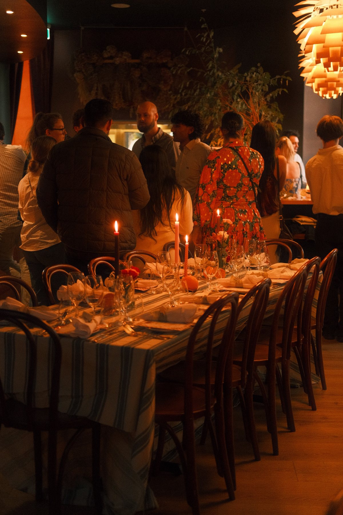 Guests gathering around a candlelit long table