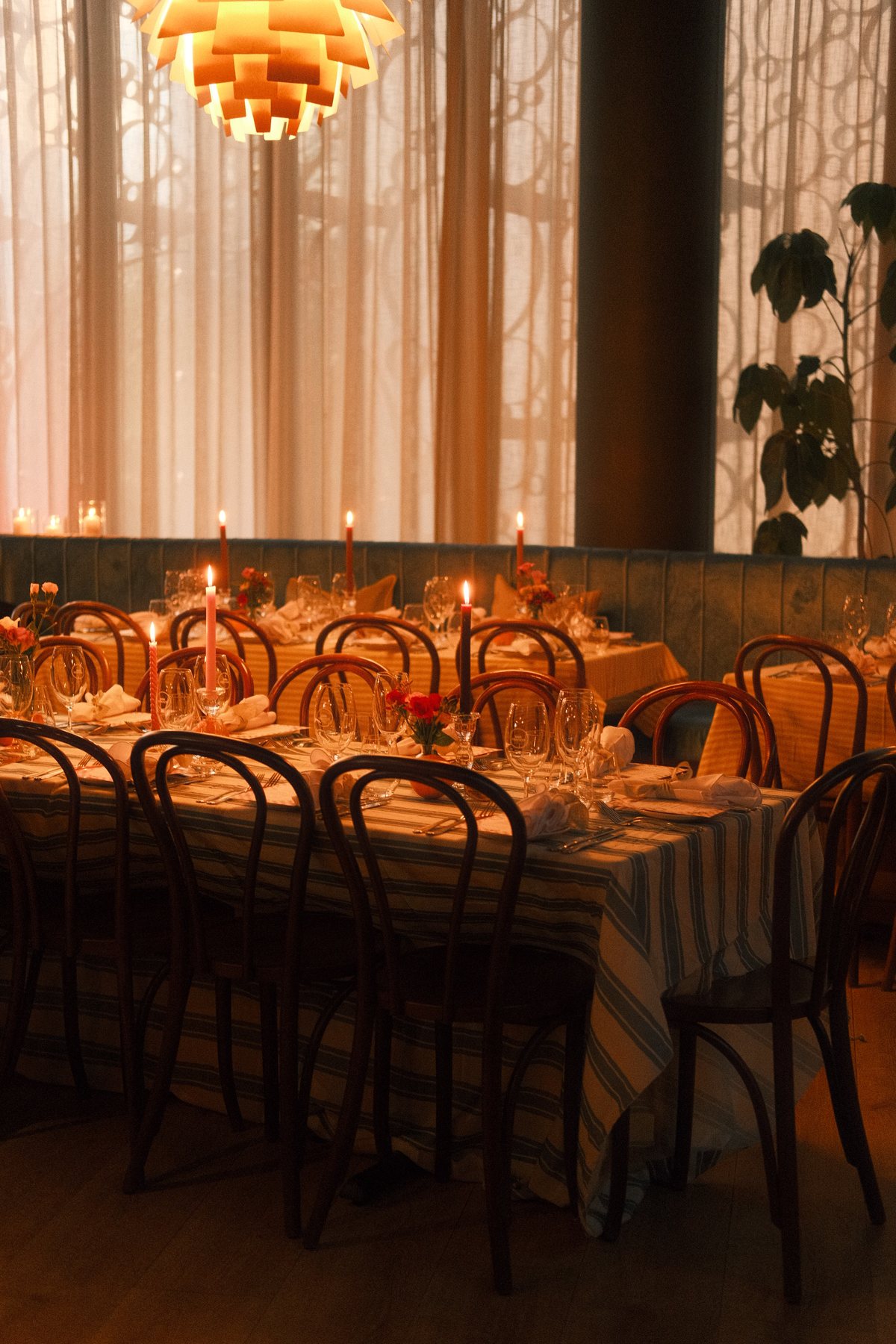 Candlelit long tables in the Restaurant under the artichoke lamp
